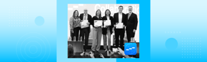 Group of professionals on stage holding certificates during a business recognition event.