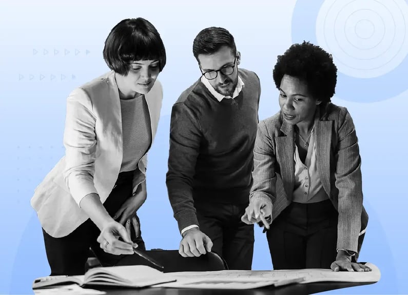 Three business people gathered around a table engaged in a collaborative discussion. A man wearing glasses speaks expressively while others listen attentively.