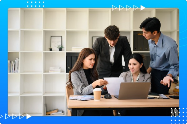 Small team gathered around a laptop reviewing data and working through decisions to align on priorities.