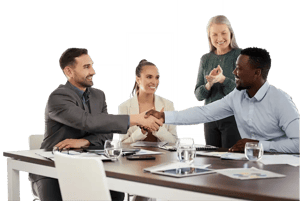 Business team shaking hands at meeting table while colleagues smile and applaud