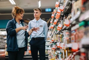 Store staff discussing products in a grocery aisle