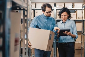 Logistics professionals coordinating package handling and inventory tracking using a tablet in a supply chain workflow